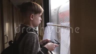 那个男孩站在火车窗口，手里拿着一块平板电脑。 坐火车旅行。 度假旅游，<strong>环游世界</strong>
